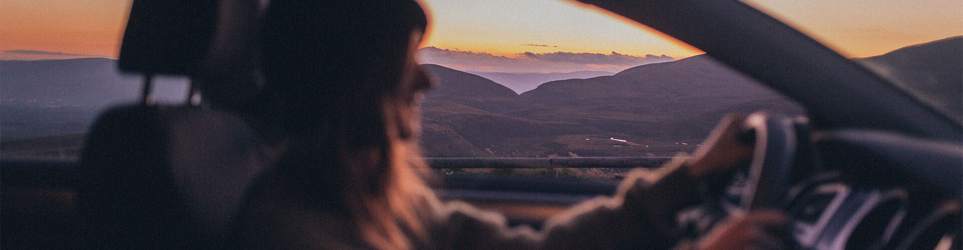 Women driving at sunset with mountainous background
